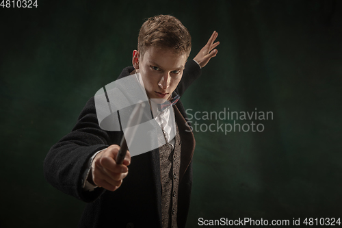 Image of Young man in art action isolated on dark green background. Retro style, comparison of eras concept.