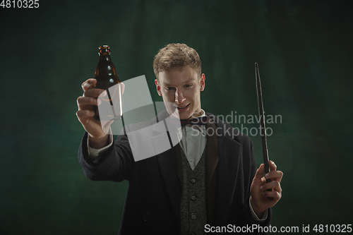 Image of Young man in art action isolated on dark green background. Retro style, comparison of eras concept.