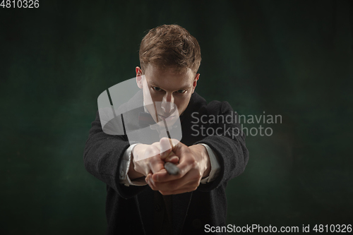 Image of Young man in art action isolated on dark green background. Retro style, comparison of eras concept.