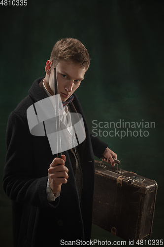 Image of Young man in art action isolated on dark green background. Retro style, comparison of eras concept.