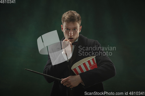 Image of Young man in art action isolated on dark green background. Retro style, comparison of eras concept.