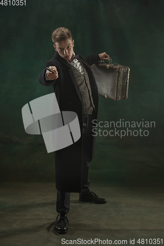 Image of Young man in art action isolated on dark green background. Retro style, comparison of eras concept.