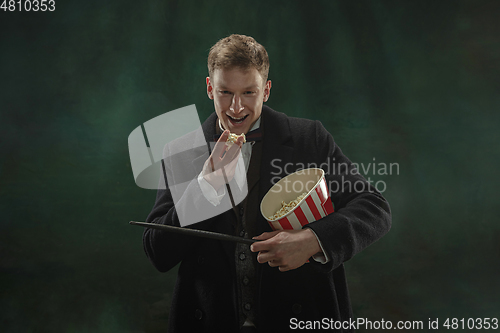 Image of Young man in art action isolated on dark green background. Retro style, comparison of eras concept.