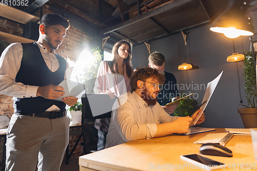 Image of Colleagues working together in modern office using devices and gadgets during creative meeting