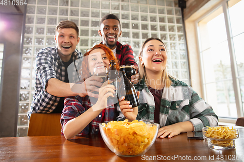 Image of Group of friends watching sport match together. Emotional fans cheering for favourite team, watching on exciting game. Concept of friendship, leisure activity, emotions