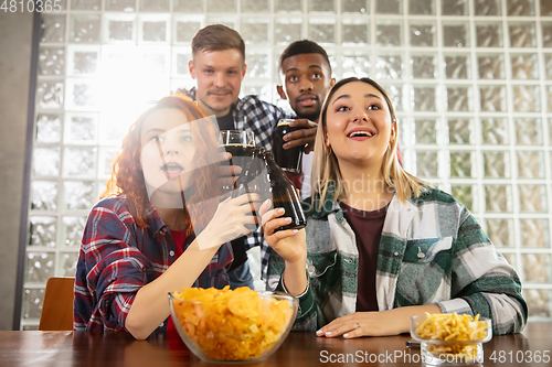 Image of Group of friends watching sport match together. Emotional fans cheering for favourite team, watching on exciting game. Concept of friendship, leisure activity, emotions