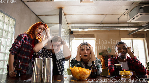 Image of Group of friends watching sport match together. Emotional fans cheering for favourite team, watching on exciting game. Concept of friendship, leisure activity, emotions