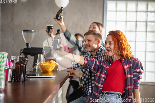 Image of Group of friends watching sport match together. Emotional fans cheering for favourite team, watching on exciting game. Concept of friendship, leisure activity, emotions