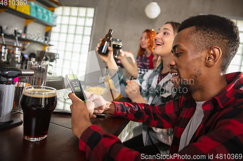 Image of Group of friends watching sport match together. Emotional fans cheering for favourite team, watching on exciting game. Concept of friendship, leisure activity, emotions