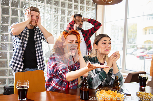 Image of Group of friends watching sport match together. Emotional fans cheering for favourite team, watching on exciting game. Concept of friendship, leisure activity, emotions