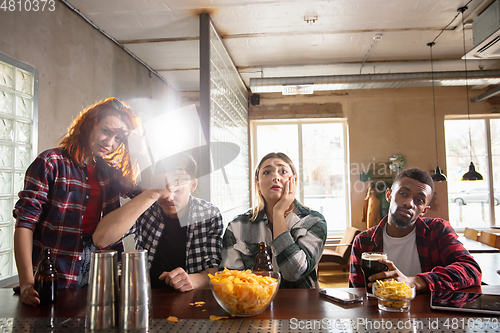 Image of Group of friends watching sport match together. Emotional fans cheering for favourite team, watching on exciting game. Concept of friendship, leisure activity, emotions