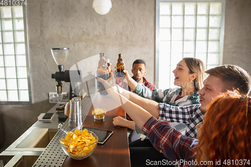 Image of Group of friends watching sport match together. Emotional fans cheering for favourite team, watching on exciting game. Concept of friendship, leisure activity, emotions