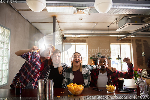 Image of Group of friends watching sport match together. Emotional fans cheering for favourite team, watching on exciting game. Concept of friendship, leisure activity, emotions