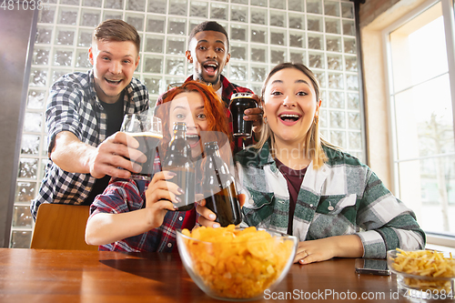 Image of Group of friends watching sport match together. Emotional fans cheering for favourite team, watching on exciting game. Concept of friendship, leisure activity, emotions