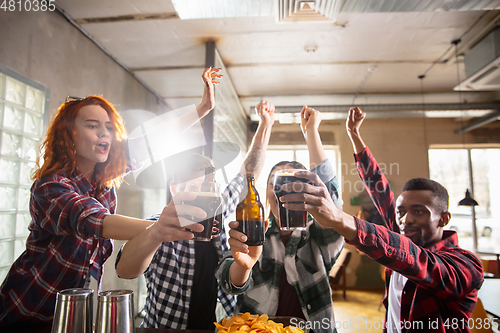 Image of Group of friends watching sport match together. Emotional fans cheering for favourite team, watching on exciting game. Concept of friendship, leisure activity, emotions