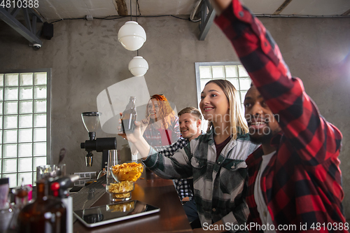 Image of Group of friends watching sport match together. Emotional fans cheering for favourite team, watching on exciting game. Concept of friendship, leisure activity, emotions