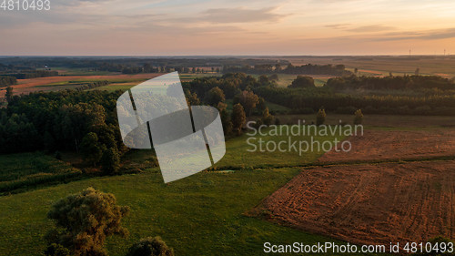 Image of Colorful sunset over forest and fields aerial