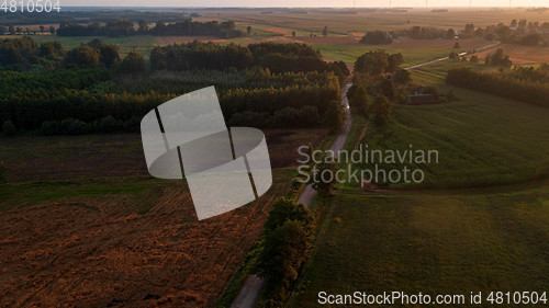 Image of Colorful sunset over forest and fields aerial