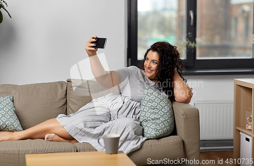 Image of happy woman taking selfie with smartphone at home