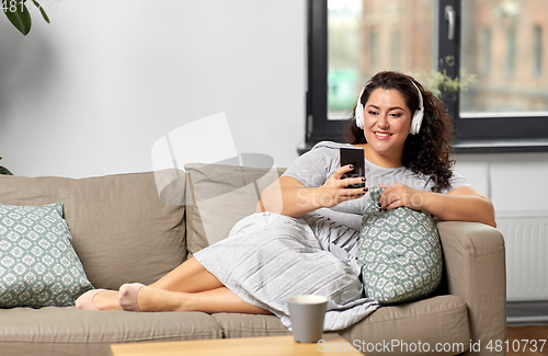 Image of woman in headphones listens to music on smartphone