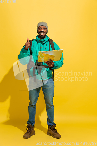 Image of Full length portrait of a cheerful young african tourist guy isolated on yellow background