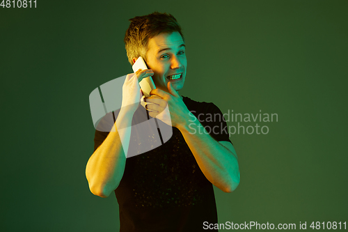 Image of Caucasian man\'s portrait isolated on green studio background in neon light