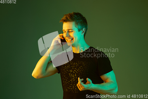 Image of Caucasian man\'s portrait isolated on green studio background in neon light
