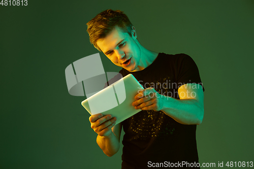 Image of Caucasian man\'s portrait isolated on green studio background in neon light