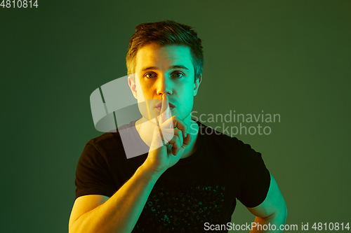 Image of Caucasian man\'s portrait isolated on green studio background in neon light