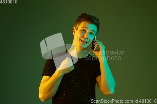 Image of Caucasian man\'s portrait isolated on green studio background in neon light