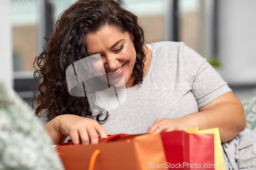 Image of happy young woman with shopping bags at home