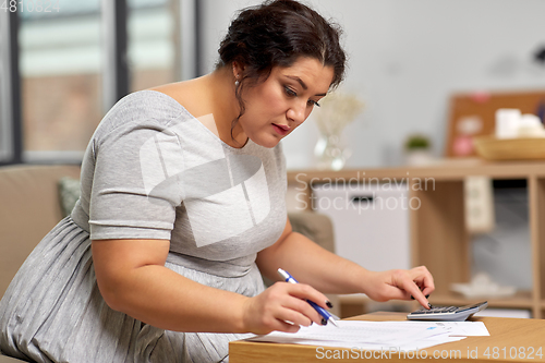 Image of woman with papers and calculator working at home