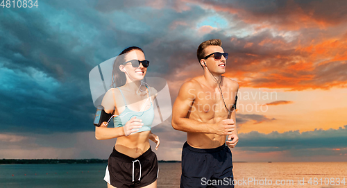 Image of couple with phones and arm bands running over sea