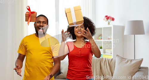 Image of happy african american couple throwing gift boxes