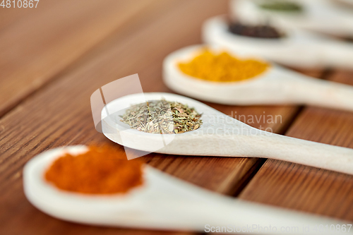 Image of spoons with different spices on wooden table