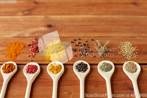 Image of spoons with different spices on wooden table