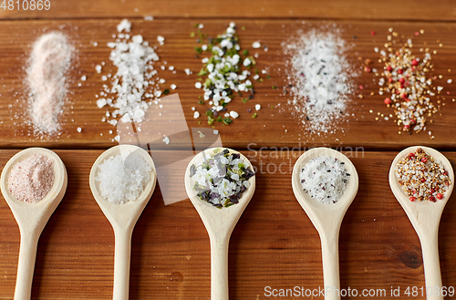 Image of spoons with salt and spices on wooden table