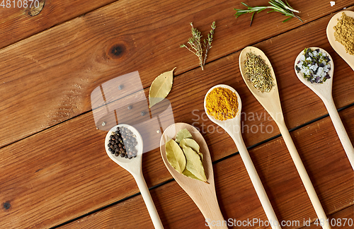 Image of spoons with spices and salt on wooden table