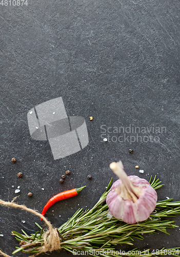 Image of rosemary, garlic and chili pepper on stone surface