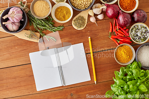Image of notebook with pencil among spices on wooden table