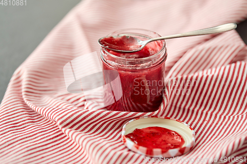 Image of mason jar with raspberry jam and spoon on towel