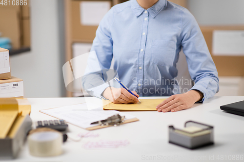 Image of woman writing on parcel envelope at post office