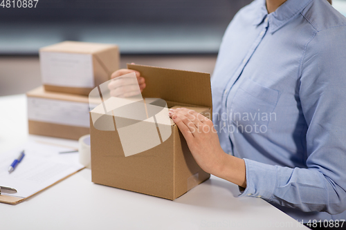 Image of woman packing parcel box at post office