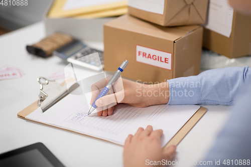 Image of hands with clipboard and parcels at post office