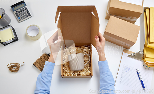 Image of hands packing mug to parcel box at post office