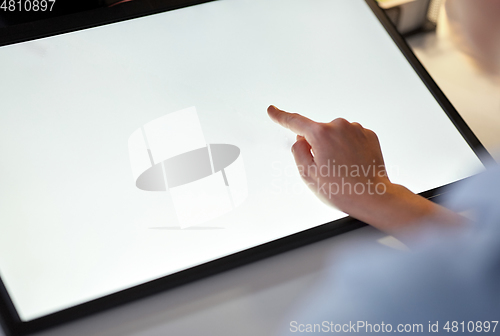 Image of hand on led light tablet at night office