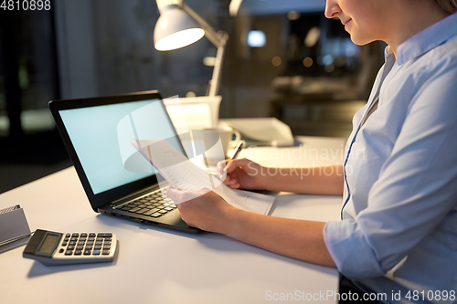 Image of businesswoman with papers working at night office