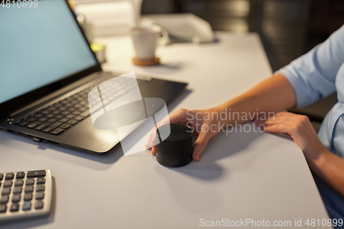 Image of hand using smart speaker at night office