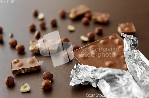 Image of milk chocolate bar with hazelnuts in foil wrapper