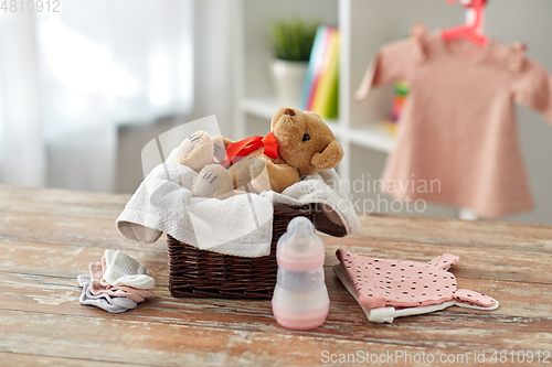 Image of teddy bear toy in basket with baby things on table